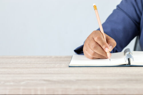 adult taking notes with pencil and paper